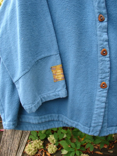 Barclay Patched Flannel Frolic Jacket Garden Blue Teal Size 2, featuring a light-blue fleece design with four wooden buttons, a contrasting patch on the sleeve, and a cozy, oversized silhouette.