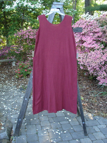 Barclay Gauze Seamless A Line Pinafore Shift Unpainted Red Wine Size 1 displayed on a wooden ladder outdoors, showcasing its A-line shape, shallow neckline, and seamless design.