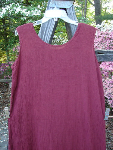 Barclay Gauze Seamless A Line Pinafore Shift Unpainted Red Wine Size 1 displayed hanging on a wooden fence, showcasing its slight A-line shape and shallow neckline.