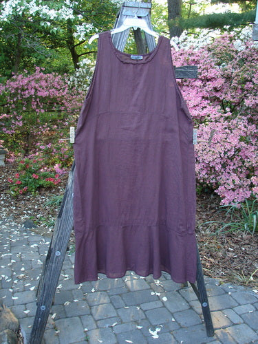 Barclay Batiste Raw Seam Flutter Pinafore Shift Unpainted Fig Size 1 displayed on a wooden ladder, showcasing its wide ruffled lower hem and raw seam rounded neckline.