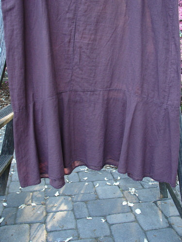 Barclay Batiste Raw Seam Flutter Pinafore Shift Unpainted Fig Size 1 displayed on a clothes rack, showcasing its ruffled lower edge and raw seam rounded neckline.