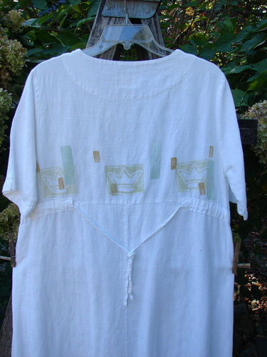 1999 Textured Linen Water Dress Tiny Fish White Size 0, featuring a lightweight, loose fit with abstract pastel appliqués and a V-shaped dropped waist, hanging outdoors against green foliage.