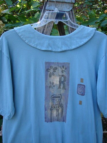 1994 Compass Top Chair Dusk Size 1: Pale-blue shirt with stylized flower and chair print, large R, abstract motifs, and functional features like side vents and an over-collar.