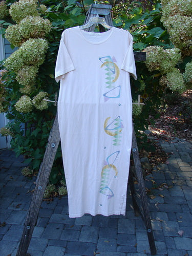 1996 Long Tea Dress Half Moon Birch Bark Size 0, features a seamless design with pastel motifs on white organic cotton. Draped on an outdoor ladder, showcasing its elegant length and unique neckline.