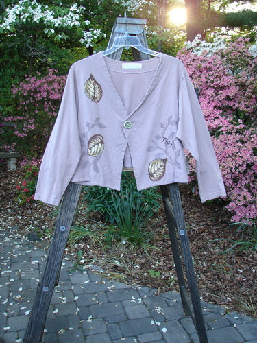 1998 Botanicals Calla Jacket Leaf Passiflora Size 1 displayed on a wooden ladder, showcasing its unique leaf-themed design, pointed front hemline, and single ceramic closure, made from organic cotton.