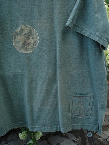 A close-up of a 1994 Short Sleeved Tee with circular fan fare design in green.