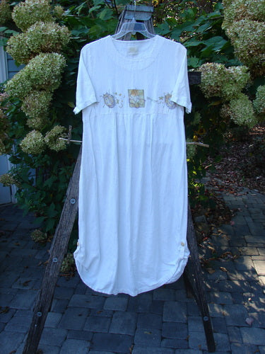 1999 Textured Linen Water Dress Garden Friends White Size 0, featuring a scooped neckline, empire waist, and mid-shin length. Displayed on an A-frame ladder, showcasing appliqués, button tabs, and pleated front.