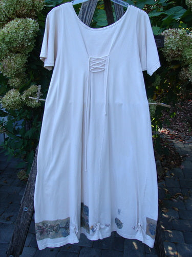 1994 Loop Dress Magic Garden Tea Dye Smaller OSFA hangs outdoors, showcasing its scooped neckline with lace-up detail, short sleeves, and flared hem with fabric insets, embodying Bluefishfinder.com's unique vintage style.