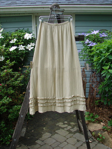 Barclay Rib Silk Triple Ruffle A Line Skirt Unpainted Sand Size 0 displayed on a rack, highlighting its full elastic waistline, flowing rib silk texture, and triple ruffle flutter detail.