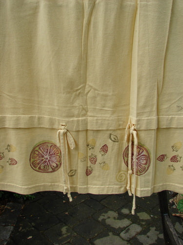 Close-up of the 1999 Basket Skirt Fruit Slice Buttercup Size 1, highlighting its medium-weight organic cotton fabric, full elastic waistband, deep side pockets, and unique fruit slice-themed bottom panel.