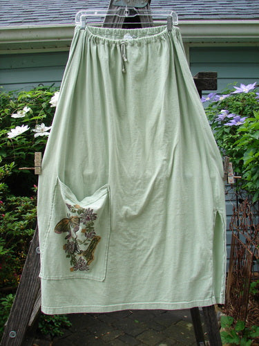 1994 Pocket Skirt Magical Garden Seawater Size 1 displayed on a clothesline, showcasing a full A-lined shape, lower front pocket with garden theme, and a drawcord waistline.