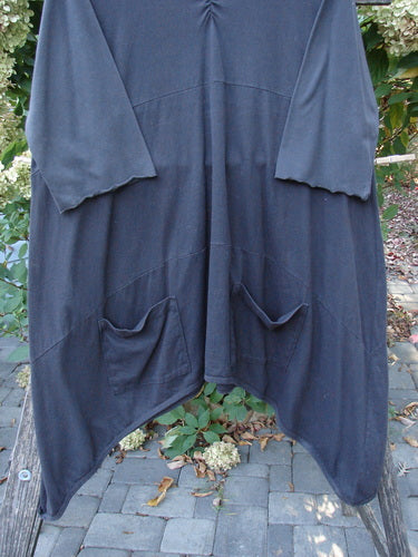 Barclay Perfect Day Dress Unpainted Black Size 2, featuring a loose fit with asymmetrical hem, slightly V-shaped neckline, oversized front pockets, and lettuce-edged sleeves, displayed on an outdoor stand.