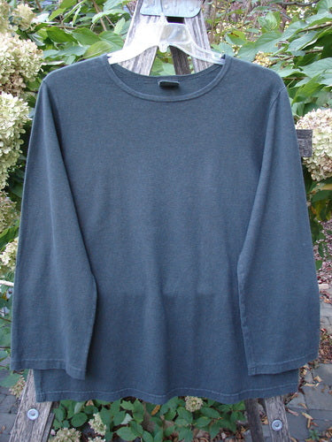 Barclay Hemp Cotton Long Sleeved Tee Unpainted Deep Forest Size 1 displayed on a hanger outdoors, highlighting its medium-weight texture, rounded neckline, and elongated shape, set against a natural backdrop.