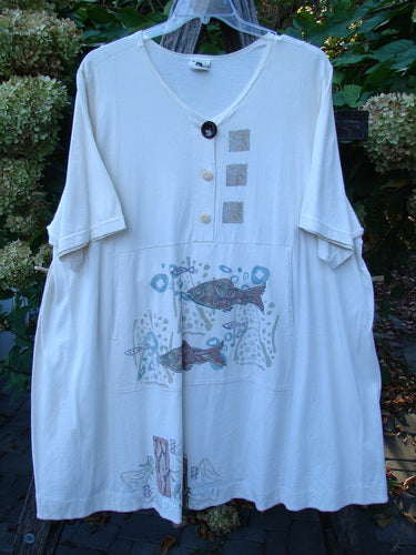 Barclay Tunnel Pocket Pull Over Dress Fish Natural Size 2 features a V-neck with mismatched buttons, fabric appliqués, and a whimsical underwater scene with fish motifs, ideal for expressing creative individuality.
