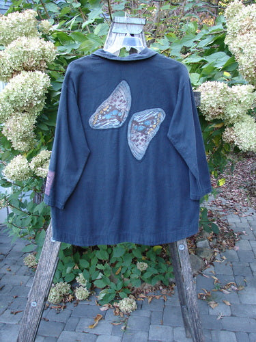 Barclay Patched Flannel PJ Pom Pom Top Pinwheel Black Size 0 displayed on a weathered ladder. Features include butterfly appliqués and playful pom-poms, surrounded by lush greenery and white hydrangeas.