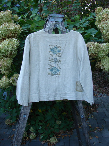 1999 Summercloth Hemp Crop Jacket Nature Cement Size 1 draped on wooden stepladder. Features include muted motifs on the back, square fabric patch, metal buttons, and drop shoulders, embodying BlueFishFinder's vintage elegance.