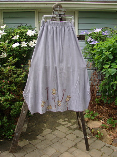 1998 Botanicals Gillyflower Skirt Bud Wisteria Size 2 displayed on a rack, featuring a palm tree design and curvy exterior seams, with an elastic waistband and unique widening-narrowing hem.