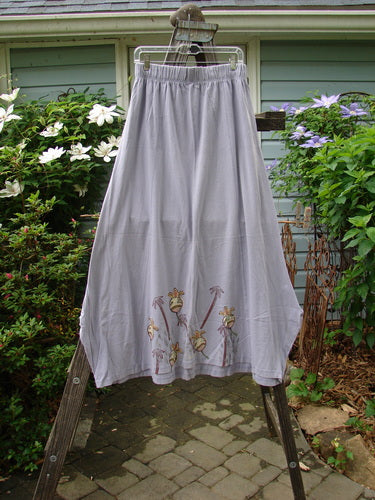 1998 Botanicals Gillyflower Skirt Bud Wisteria Size 2 hanging on a clothesline, showcasing its full elastic waistband, sectional curvy exterior seams, and specialized hem adorned with garden bud theme paint.