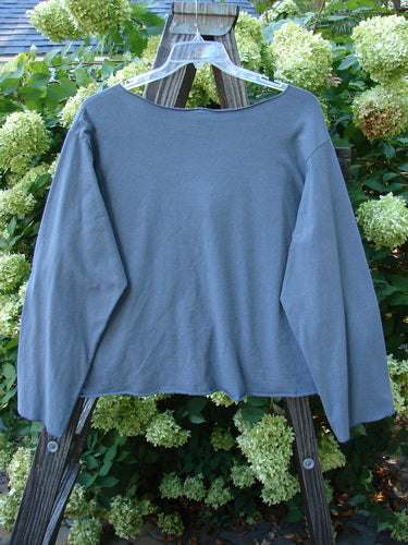 Barclay NWT Layering Cardigan Shrug Rain Flower Blue Dusk Size 2 displayed on a wooden stand, showcasing its long sleeves, open front, varying hemline, and artistic rain flower detailing.