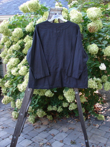 2000 Batiste Overshirt Top Unpainted Black Size 2 displayed on a wooden rack, showcasing its light, airy fabric and distinctive drop waist seam with a slight flounce, perfect for a breezy, vintage style.