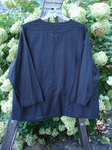 2000 Batiste Overshirt Top Unpainted Black Size 2 displayed on a hanger, showcasing its boxy shape, drop waist seam with flounce, and softly rounded V-neckline, emphasizing its light, airy fabric.