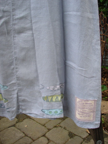 Close-up of the 1999 Handkerchief Linen Sunbeam Dress, showcasing its full-length sweeping skirt, empire waist seam, and sectional panels with a sweet fish theme paint design.