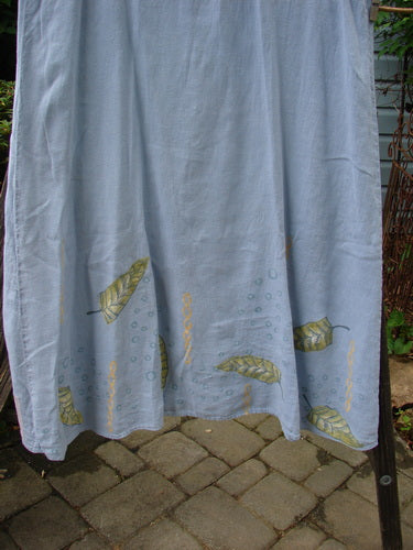 1999 Handkerchief Linen Sunbeam Dress, Leaf Water Size 1, hanging on a clothesline, showcasing its sweeping skirt and sectional panels with a sweet leaf theme.