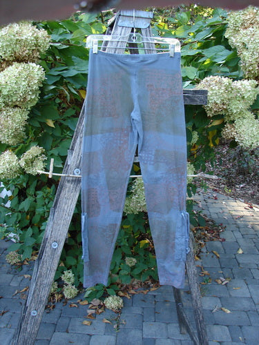 Barclay Cotton Lycra Side Gather Legging Lattice Moss Size 0 displayed on a hanger, highlighting its tapered design with exterior drawcords and elastic waistband, set against a garden background.