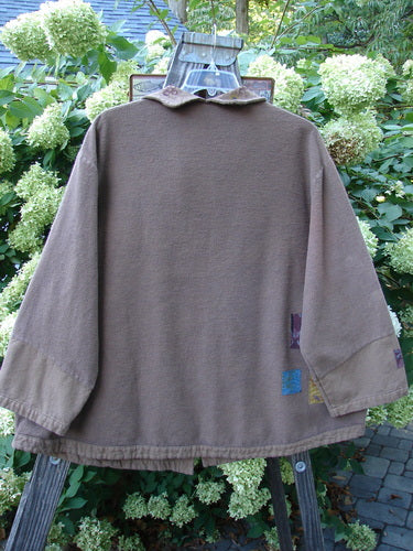 Barclay Patched Flannel Frolic Jacket Vine Garden Rock Size 2 displayed on a swing, showcasing its oversized front pocket, unique buttons, contrasting lower sleeves, and painted patches in a vine garden theme.