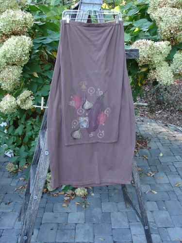 Barclay Button Panel Skirt Vegetable Sepia Size 2 draped on a ladder, features a still-life fruit motif, elastic waistband, and side buttons, showcasing its elegant drape and artistic design.