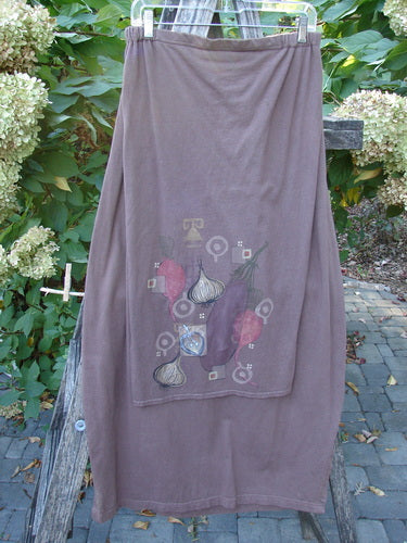Barclay Button Panel Skirt Vegetable Sepia Size 2, featuring a harvest-themed print of vegetables, displayed outdoors on a wooden frame with a unique wrap style and accent side buttons.