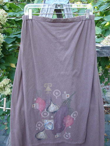Barclay Button Panel Skirt Vegetable Sepia Size 2, featuring a stylized vegetable motif, hangs outdoors. Made from organic cotton with a painted harvest theme and accent side buttons.