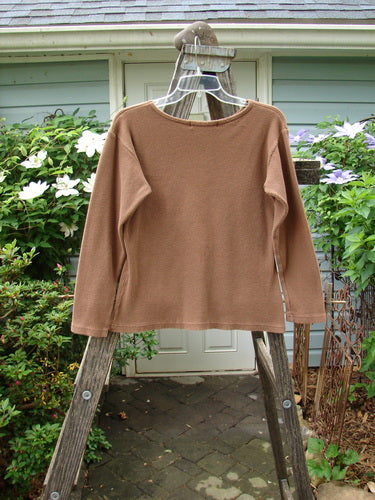 1997 Long Sleeved Thermal Top Unpainted Copper Size 1 displayed on a wooden rack, showcasing its thick cotton thermal fabric and slightly tapered waistline, ideal for cozy layering.