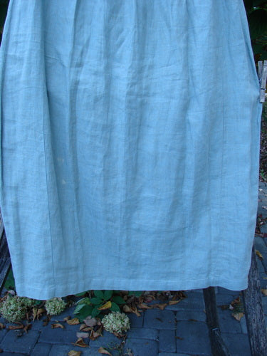 2000 Cross Dye Linen Contour Skirt in Unpainted Meadow hangs outdoors, showcasing its medium-weight fabric and unique vertical panels, embodying BlueFishFinder's vintage style and creative expression ethos.