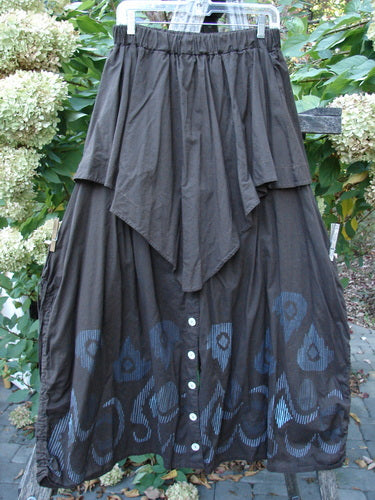 Barclay Batiste Split Button Pant Skirt Celtic Mocha Size 0, features a billowy, layered design with front buttons and Celtic-themed graphics along the hem, elegantly displayed against lush greenery.