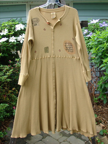 1995 Thermal Soliloquy Dress in Architectural Burnished Gold, Size 2, displayed hanging. Features ribbed accents, tiny front snaps, sweeping hemline, and abstract paint theme. Perfect condition, mid-weight cotton thermal fabric.