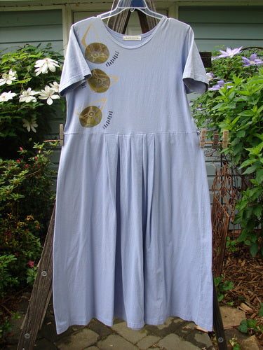 1997 Lawn Dress Side Geo Freesia Size 1 hanging on a clothesline, featuring a planetary pattern, tailored pleats, and a drop waistline, made from organic cotton.