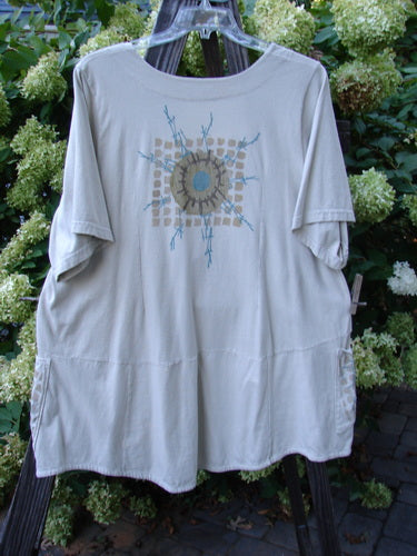 A white shirt with a blue design on it, featuring a squared double-paneled deeper neckline, empire waist seam, wide full pleats, and a forever skirt flair. Painted in the moon and twig theme, this Barclay Be There Top in Dust is made from organic cotton. Size 2.