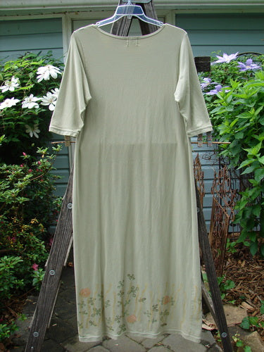 The 2001 Tide Dress Jax Kelp Size 1 on a wooden rack showcases a long, white, slightly flared dress with three-quarter length sleeves, ideal for layering or wearing alone.