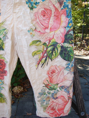 Magnolia Pearl Applique Benjamin Overall Birdie Bouquet Moon OSFA features vintage-style floral motifs with pink roses and green leaves on cream fabric, visible with distressed edges and textured stitchery. Hanging outdoors on patio.