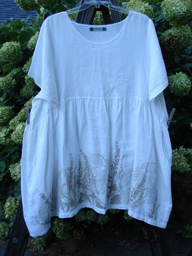 Barclay Linen Studio Pullover Dress Breeze Fern White Size 2 displayed on a swing, showcasing its flouncy lower skirt, gathered waistline, wide hem sweep, and unique figure 8 front bodice seams.