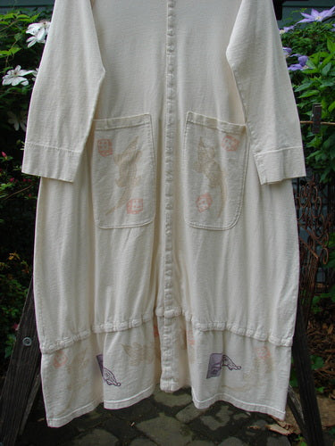 2001 T Snap Dress Game Pieces Fizz Size 1 features a white organic cotton dress with three-quarter sleeves, snap tape, triangular pockets, and painted designs, showcasing a flowing A-line shape and V neckline.