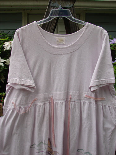 1999 Ribbon Dress Butterfly Orchid Size 2 on hanger, showcasing double-paneled rounded neckline, adjustable empire waist, buttonhole accents, and slight bell shape. Made from organic cotton, part of the 1999 Summer Collection.