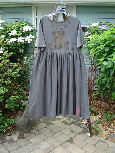 1992 Short Sleeved Simple Dress Vase Black Sand Size 1 displayed on a mannequin, showcasing its semi-dropped waistline, full draping lower, and uniquely placed Blue Fish patch with vase design.