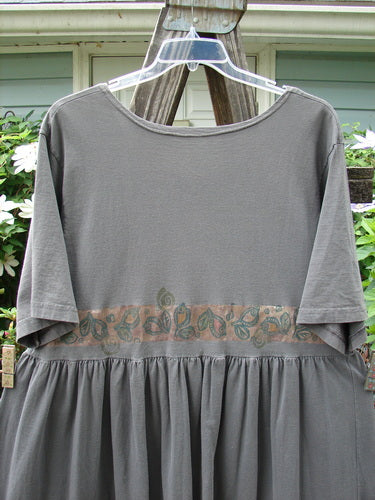 1992 Short Sleeved Simple Dress Vase Black Sand Size 1 displayed on a hanger, showcasing its semi-dropped waistline, full draping lower, deeper rounded neckline, short sleeves, and unique Blue Fish patch.