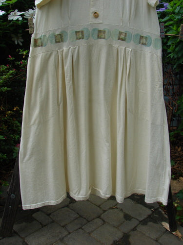 2000 LuLu's Dress Moon Window Milk Size 2: A white dress with a patterned design hanging on a clothesline, featuring a drop yoked waistline, inseam pockets, button closure, and pleated front darts.