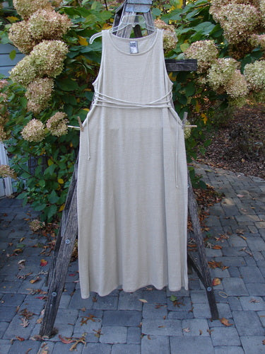 1998 Linen Knit Wrap Dress Unpainted Natural Size 1, elegantly displayed on a wooden ladder in an outdoor setting, showcasing its graceful drape, rounded neckline, and flowing silhouette amid lush hydrangeas.