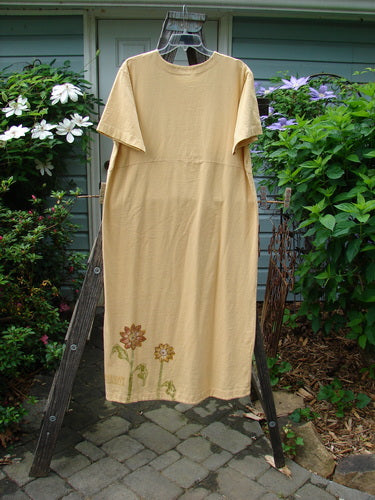 1998 Botanicals Calla Dress Tall Sunflower Sundial Dress Size 1 displayed on a swing, showcasing a softly folded neckline, drop shoulders, pegged shape, upward scooped hemline, and tall sunflower theme.