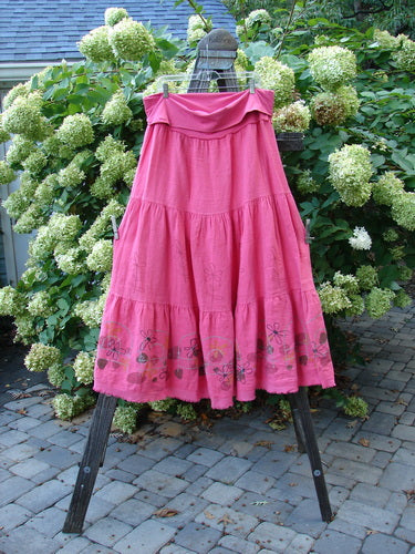 Barclay Linen Fold Over Three Tier Skirt Daisy Flamingo Size 2 displayed on a clothes rack, showcasing its triple horizontal tiers and frayed lower hem, epitomizing vintage Blue Fish Clothing's creative and expressive style.