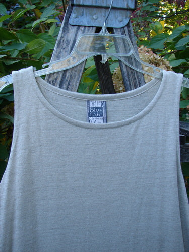 1998 Linen Knit Wrap Dress Unpainted Natural Size 2, displayed on a clear hanger, features a sleeveless design with a wrap bodice, smaller arm openings, and a graceful drape, embodying Blue Fish's vintage elegance.